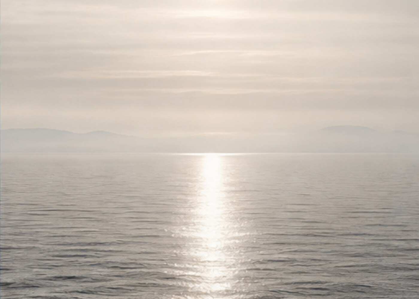 Quiet silver ocean beneath a pale sky